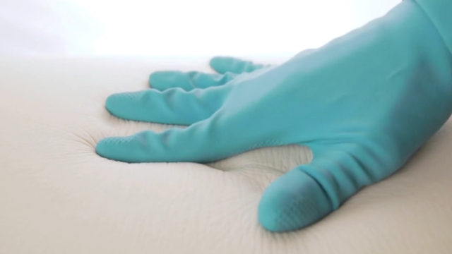 Ruka u plavoj rukavici pritiska površinu dušeka