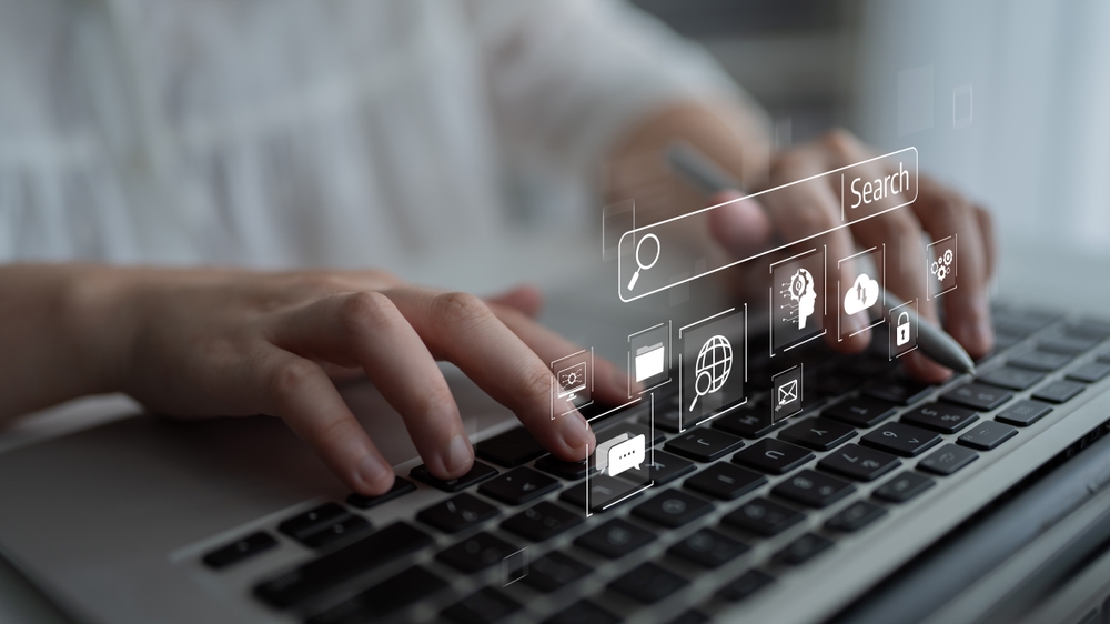 Osoba koristi laptop dok su prikazani digitalni simboli za pretragu, SEO i optimizaciju sajta.